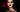 Gothic beauty portrait with smoky eyes and deep oxblood lips against a black background with a dramatic red splash