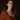 Woman in a rust brown dress with warm, sun weathered goth makeup